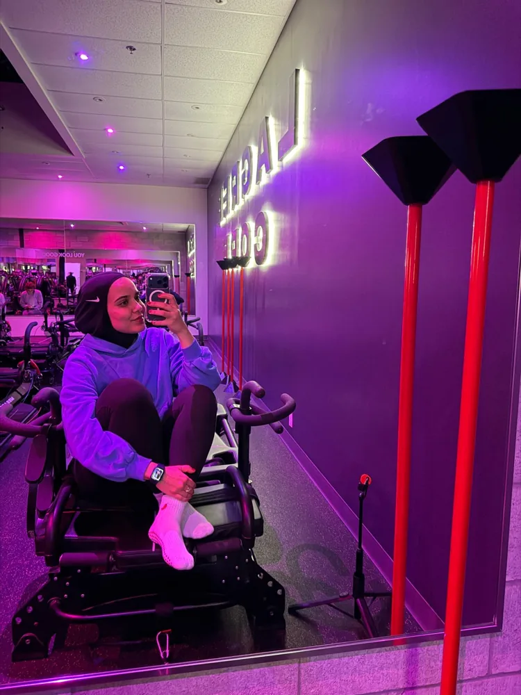 Amani, fondatrice des Runneuses, assise sur une machine dans un studio de pilates éclairé en violet