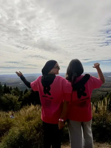Deux Runneuses en t-shirt rose, bras ouverts face à la vallée