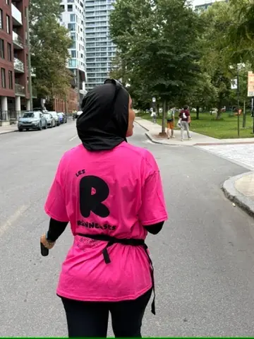 Une Runneuse de dos en t-shirt rose orné du R du club