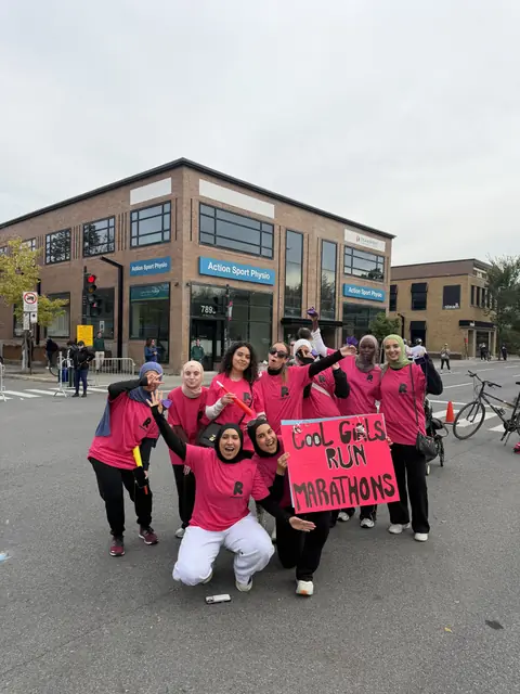 Runneuses en rose avec leur pancarte au bord du parcours du marathon