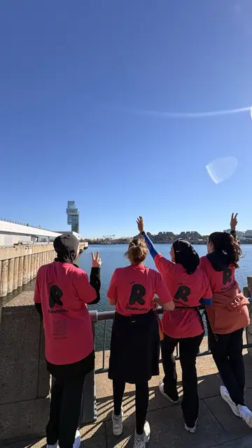 Quatre Runneuses en t-shirt rose sur un pont sous un ciel bleu